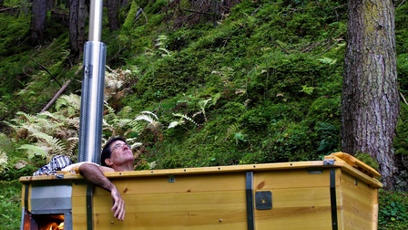 Holzwanne mit einem Mann darin im Wald