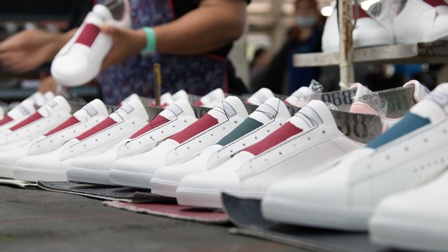 Detailansicht mehrerer weißer Sneaker mit farblichen Elementen in der Herstellung