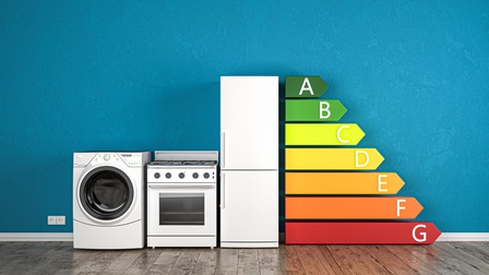 Abbildung von Elektronikgeräten mit der Anzeige der Energieeffizienzklassen vor einer blauen Wand