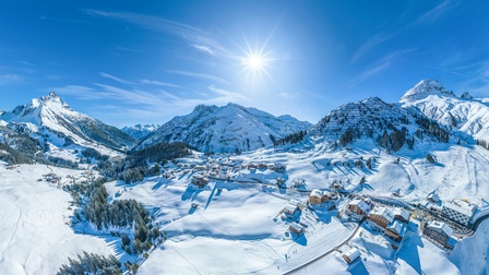Verschneite Wintersportregion am Arlberg bei blauem Himmel und Sonnenschein, Vogelperspektive