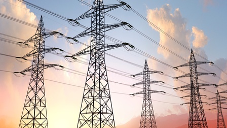 Viele neben- und hintereinander stehende Starkstrommasten unter rötlichem Himmel.