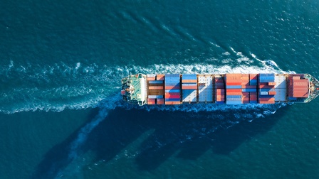 Aufnahme eines Frachtschiffs aus der Vogelperspektive, das auf einem Gewässer fährt