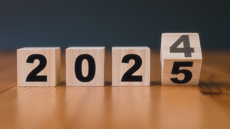 Vier Holzwürfel liegen auf einem dunklen Holztisch. Auf den Würfeln sind die Zahlen 2024 abgebildet, beim letzten Würfel geht die Zahl in die 5 über. Es wird der Jahreswechsel mit Symbolen dargestellt. <br />
