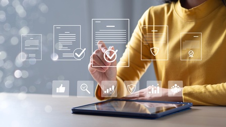 berkörper einer Person in einem gelben Oberteil an einem Tisch mit einem Tablet. Die Person berührt mit einem Finger eine eingeblendete grafische Benutzeroberfläche. Darüber sind mehrere stilisierte Dokumente mit Symbolen wie Häkchen