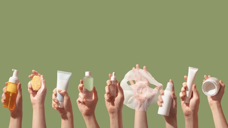 Vor grünem Hintergrund sind dreizehn Hände in die Luft gestreckt. Jede Hand hält ein anderes Pflegeprodukt, zum Beispiel eine Tube, einen Schwamm, eine Gesichtsmaske, eine Dose, eine Pumpflasche etc