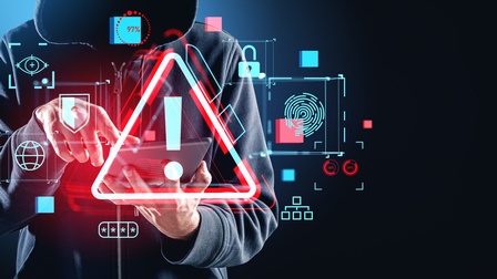 Person mit über den kopf gezogenen Kapuzenpullover bedient ein Tablat. Davor ist ein rotes Dreieck mit einem Rufzeichen zu sehen.