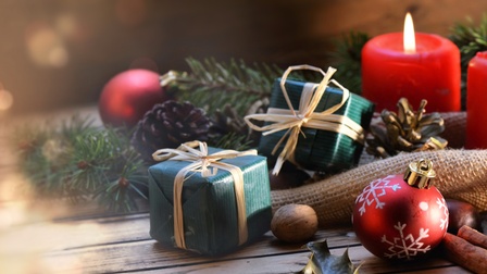 Winterliches Arrangement aus roten Kerzen, Tannenzweigen, Christbaumschmuck, Nüssen, Nelken und kleinen Geschenkpäckchen 