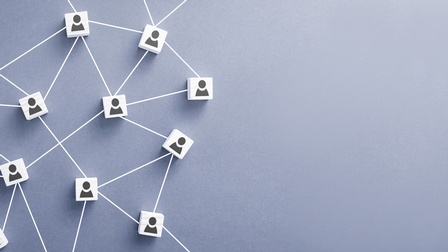 <br />
Mehrere weiße Würfel mit schwarzen Icons von Personen durch Linien verbunden auf grauem Hintergrund