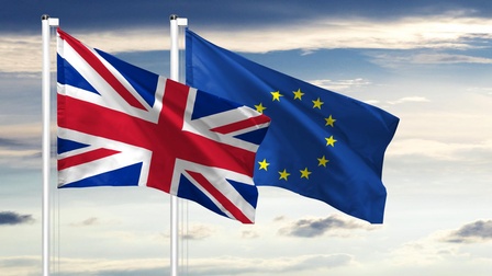 Grafik der Flagge Großbritanniens und der Flagge der Europäischen Union jeweils auf einer Fahnenstange nebeneinander vor einem bewölkten Himmel