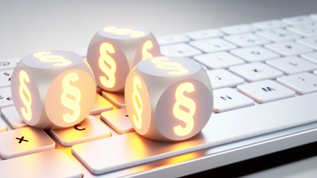 Weiße Tastatur mit drei leuchtenden Paragraphen-Würfeln