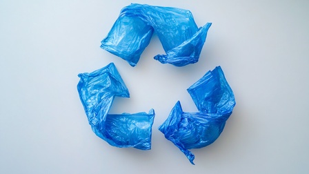 Blaue Kunststofffolie ist zu einem Recycling-Symbol angeordnet und veranschaulicht die Themen Recycling, Kreislaufwirtschaft und Abfallmanagement.