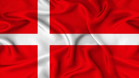 Detailansicht der dänischen Flagge mit Falten: Auf rotem Hintergrund ein weißes Kreuz, die Kreuzmitte im linken Bildbereich.