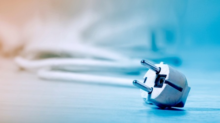 Detailansicht eines Stromsteckers mit Kabel in blauem Licht