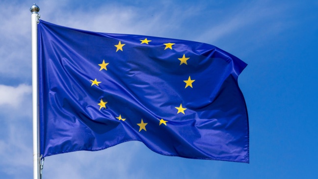 Flagge der Europäischen Union im Wind wehend, im Hintergrund blauer Himmel