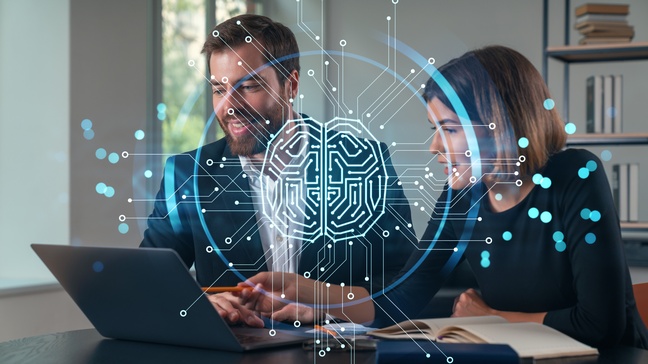 Zwei Personen sitzen hinter einem Tisch. Vor ihnen ist ein aufgeklappter Laptop. Beide blicken darauf. Über dem Bild ist eine Grafik eines Kreises, in dem verschiedene Linien und Punkte sind, die ein Gehirn darstellen.