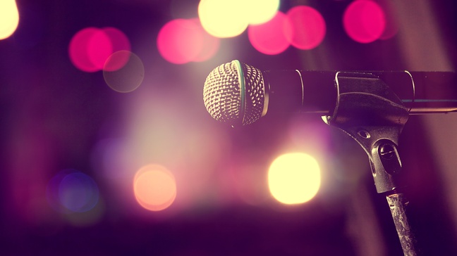 Nahaufnahme von einem Mikrofon vor einem gelb, rosa Bokeh