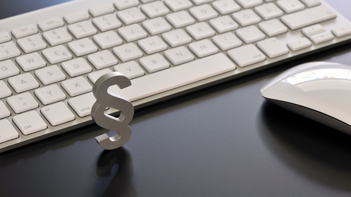 Weißes Paragrafenzeichen vor Computertastatur, daneben Computermaus