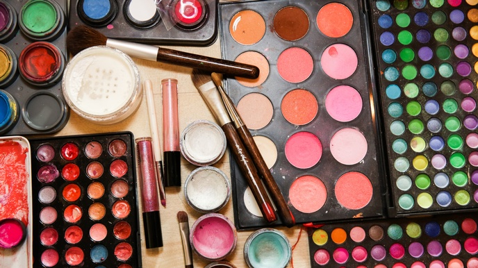 Top-Shot verschiedener Utensilien zum Schminken, wie Lidschatten, Lipgloss, Pinsel