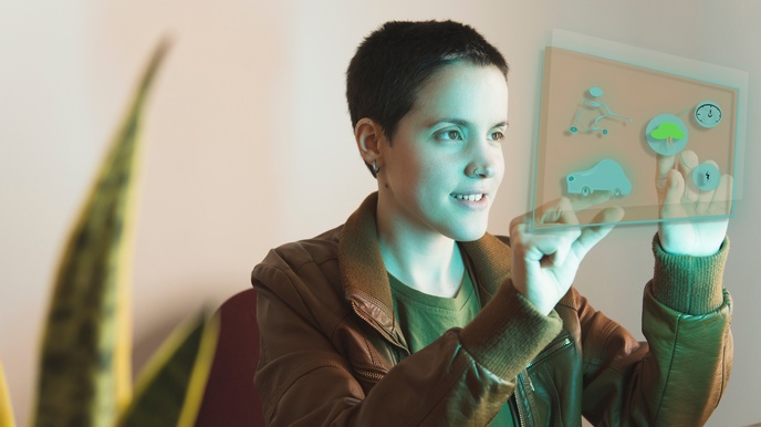 Sanft lächelnde Person mit Nasenpiercing hält beide Hände auf vor sich befindlichem grünblau leuchtendem Hologramm mit verschiedenen Grafiken: Baum, Uhr, Auto, Blitz und Figur auf Tretroller