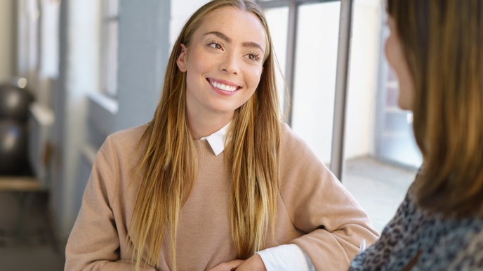 Lächelnde Person im Gespräch mit anderer Person im Ausschnitt