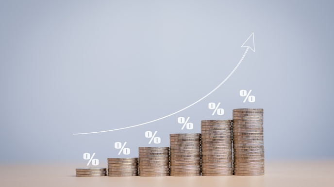 Mehrere unterschiedlich hohe Münzstapel der Größe nach aufsteigend nebeneinander positioniert, darüber jeweils weiße Prozentzeichen, schräger Strich mit links und rechts versetzter 0, sowie Pfeil der über den Stapeln nach oben deutet