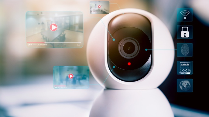 Nahaufnahme von einer Überwachungskamera, daneben sind Icons zum Thema Sicherheit sowie Miniaturbilder von Videoaufnahmen