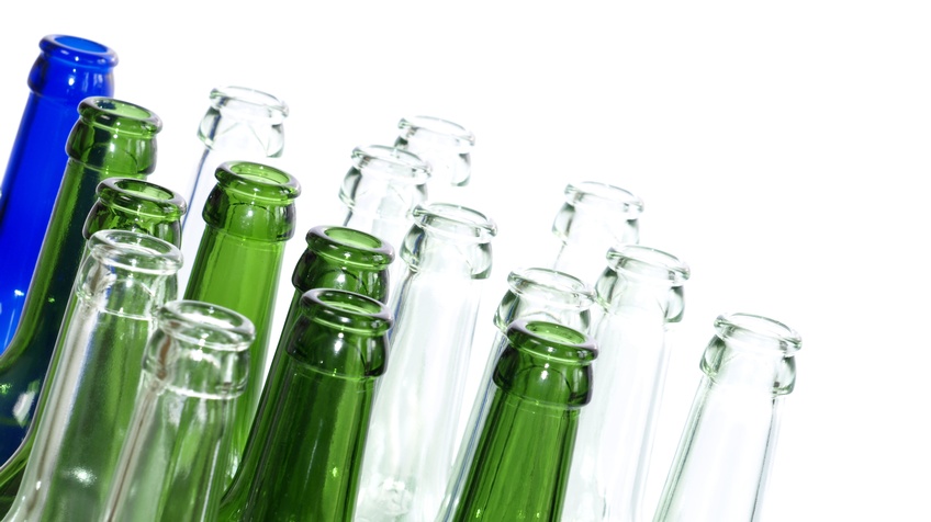 Detailsansicht leerer Glasflaschen in unterschiedlichen Farben auf weißem Hintergrund