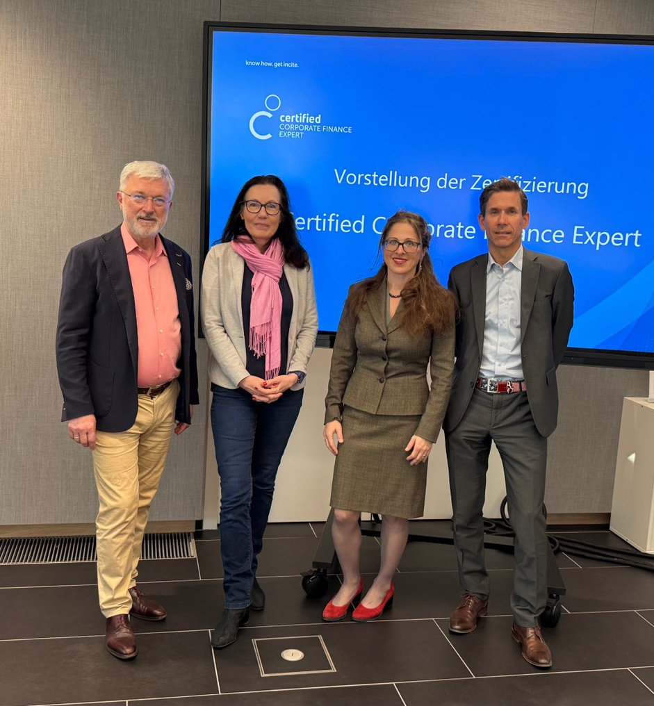 Drei Personen stehen vor einem Bildschirm während einer Veranstaltung.