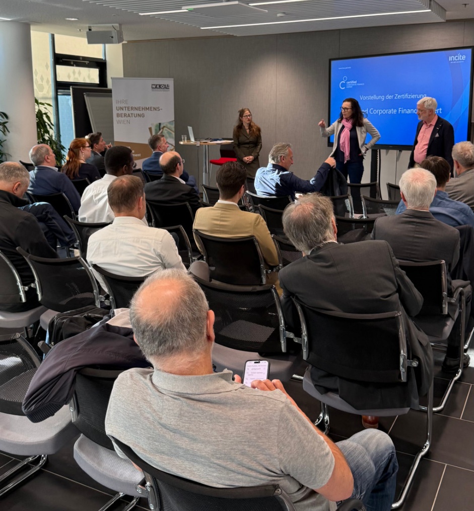 Personen sitzen während einer Veranstaltung im Publikum und hören zu.