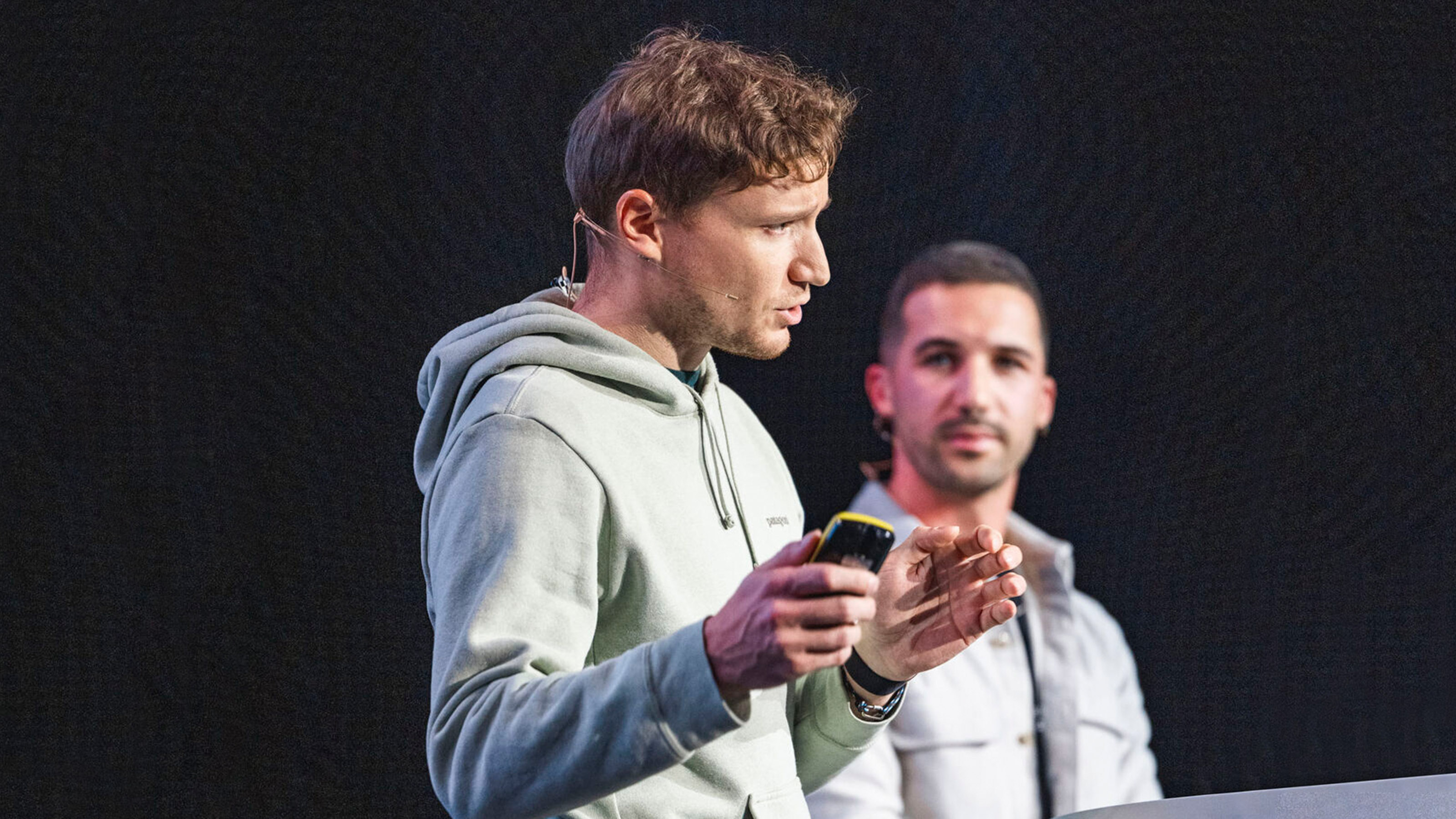 Zwei Speaker auf einer B&uuml;hne vor dunklem Hintergrund