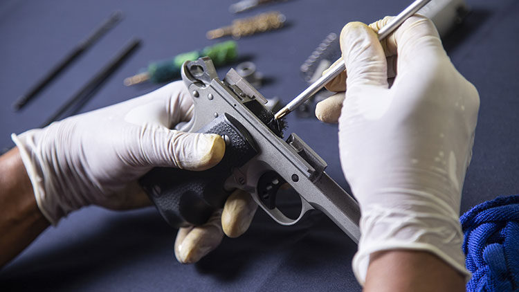 H&auml;nde halten einen Revolver, der gereinigt wird