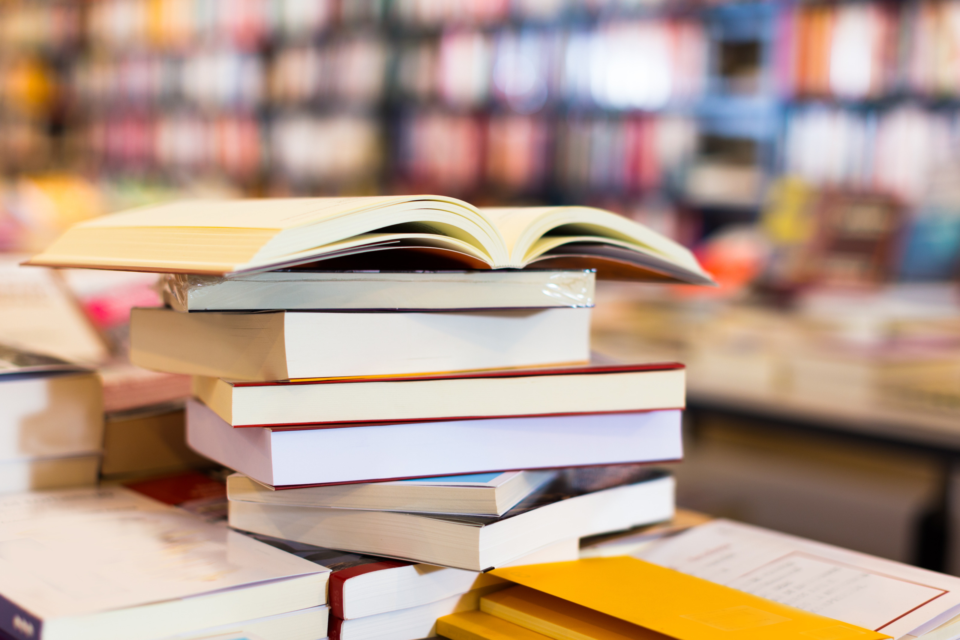 B&uuml;cherstapel mit einem aufgeschlagenen Buch vor einem verschwommenen Hintergrund