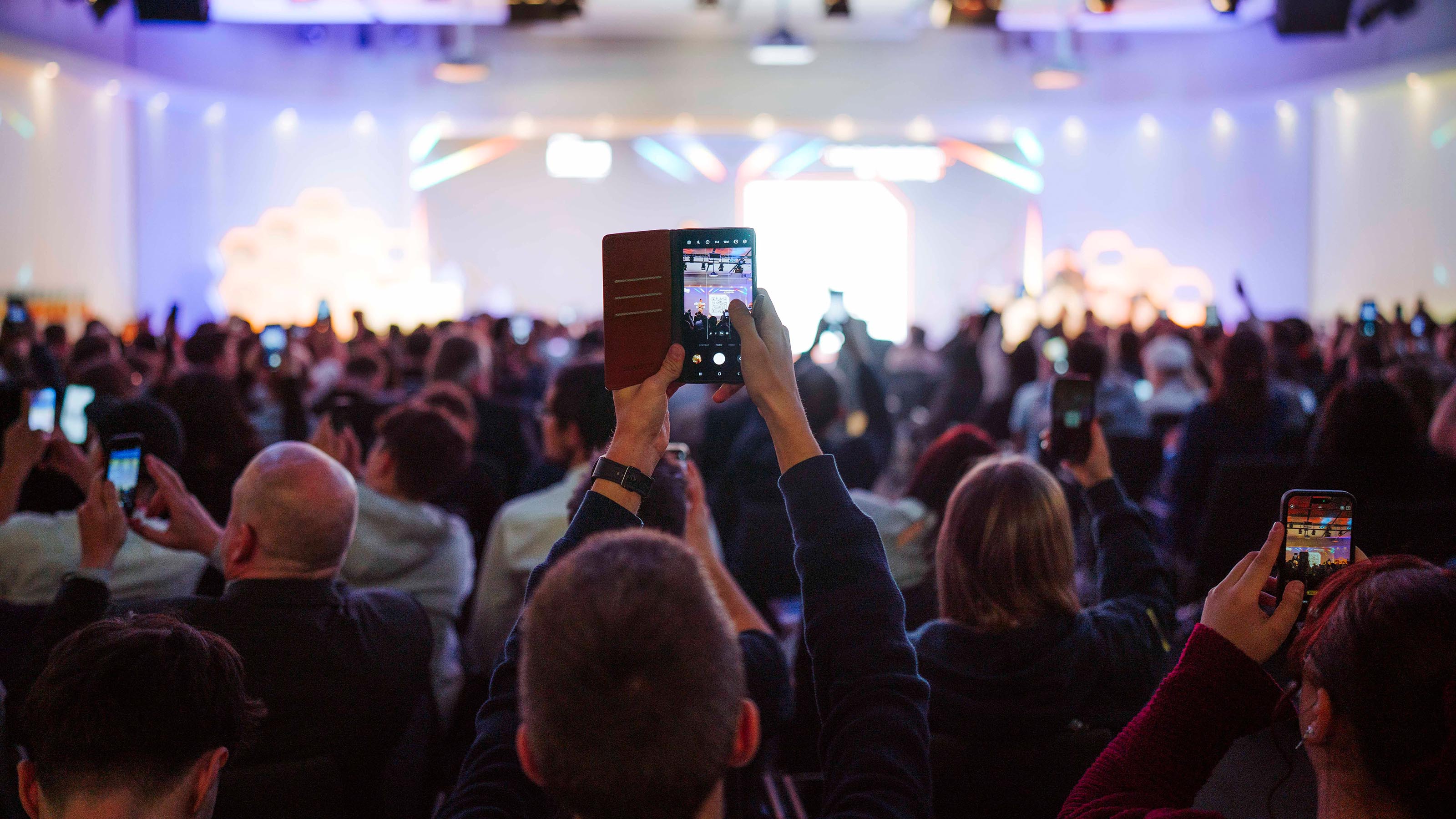 Aus dem Publikum ragt ein Handy, das die B&uuml;hne fotografiert