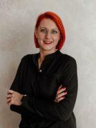 Eine Frau mit schwarzer Bluse, roten Haaren und Brillen.