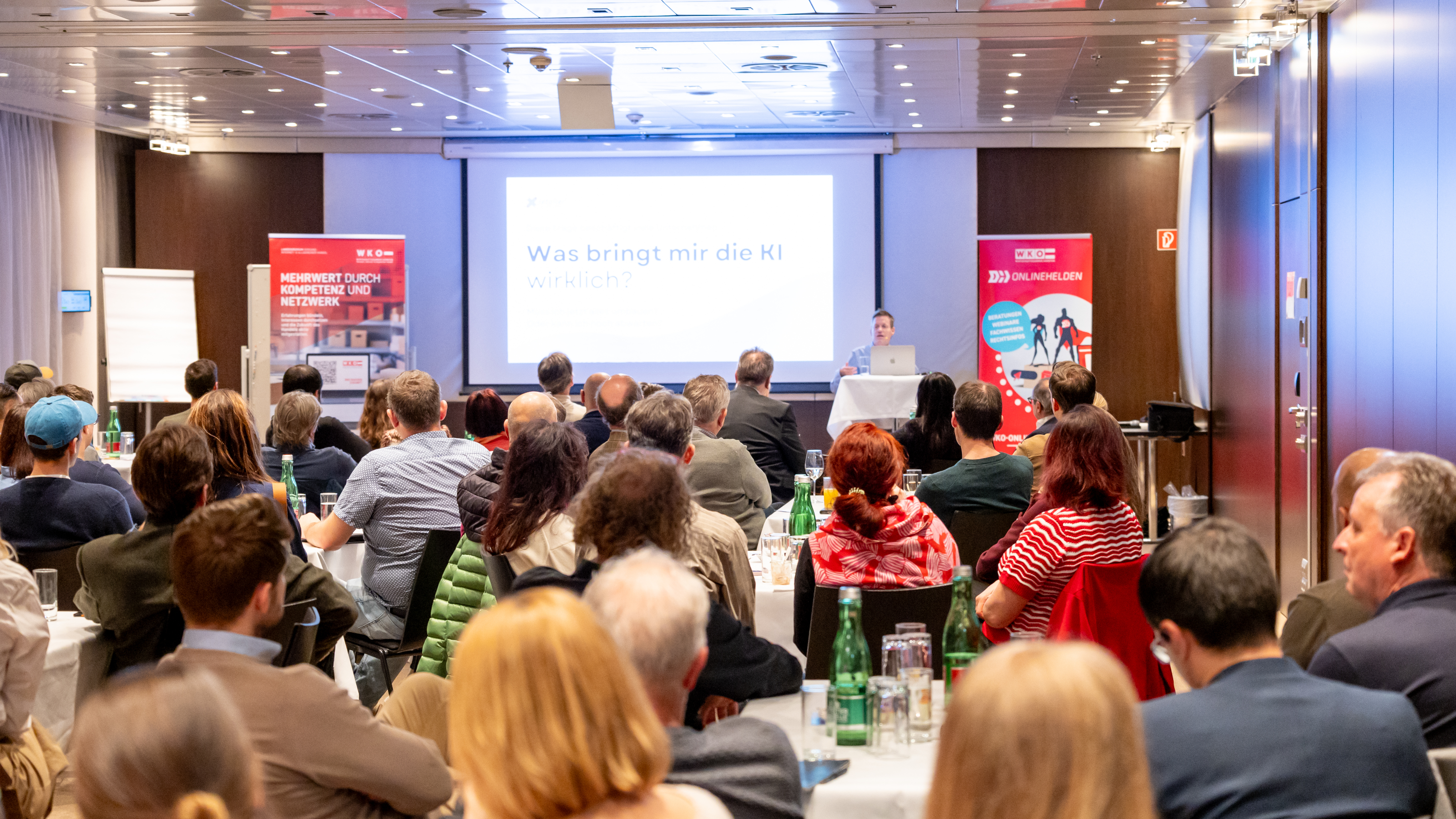 Personen sitzen in einem Raum und h&ouml;ren einem Vortrag zu