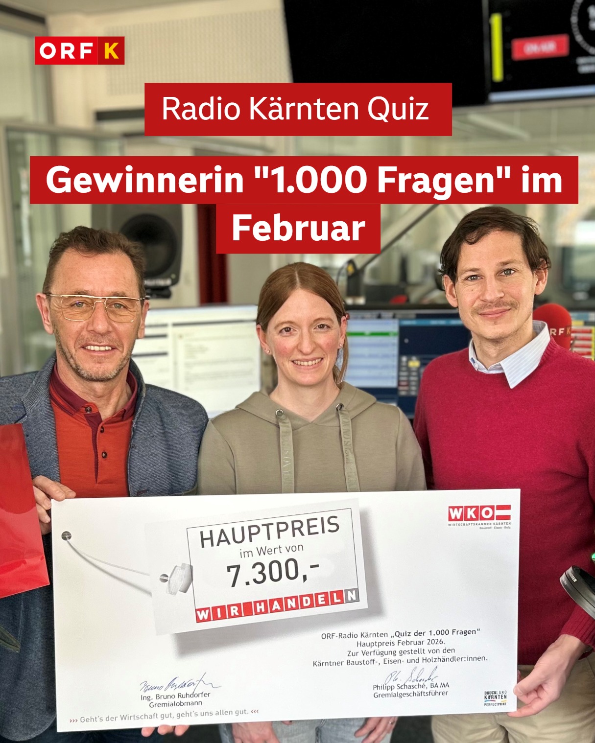 Frau in der Mitte und Mann links und rechts von ihr lachen in die Kamera. Sie halten einen riesigen Gutschein