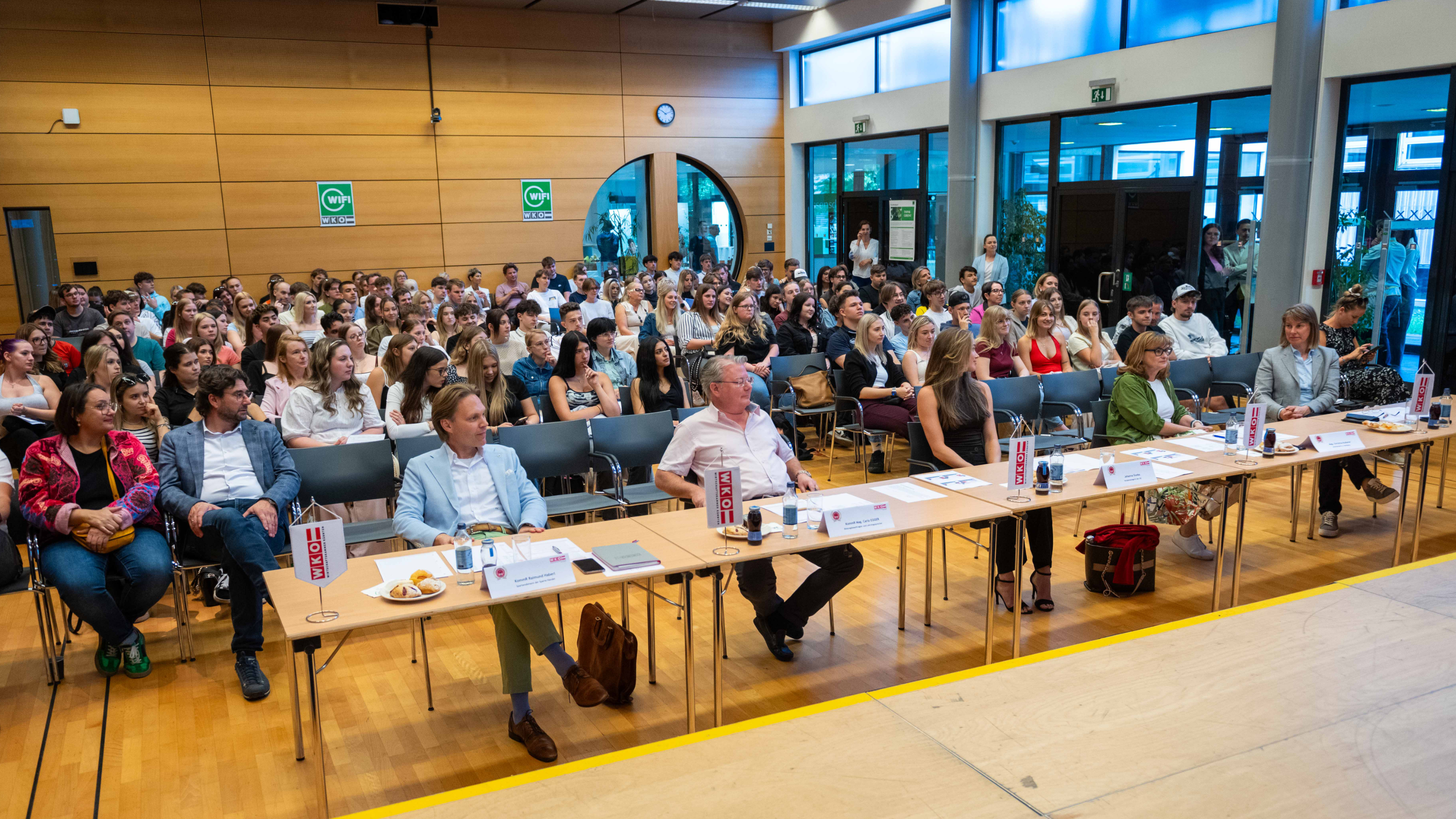 ein Raum voller sitzender Zuschauer, vorne eine Tischreihe mit der Jury