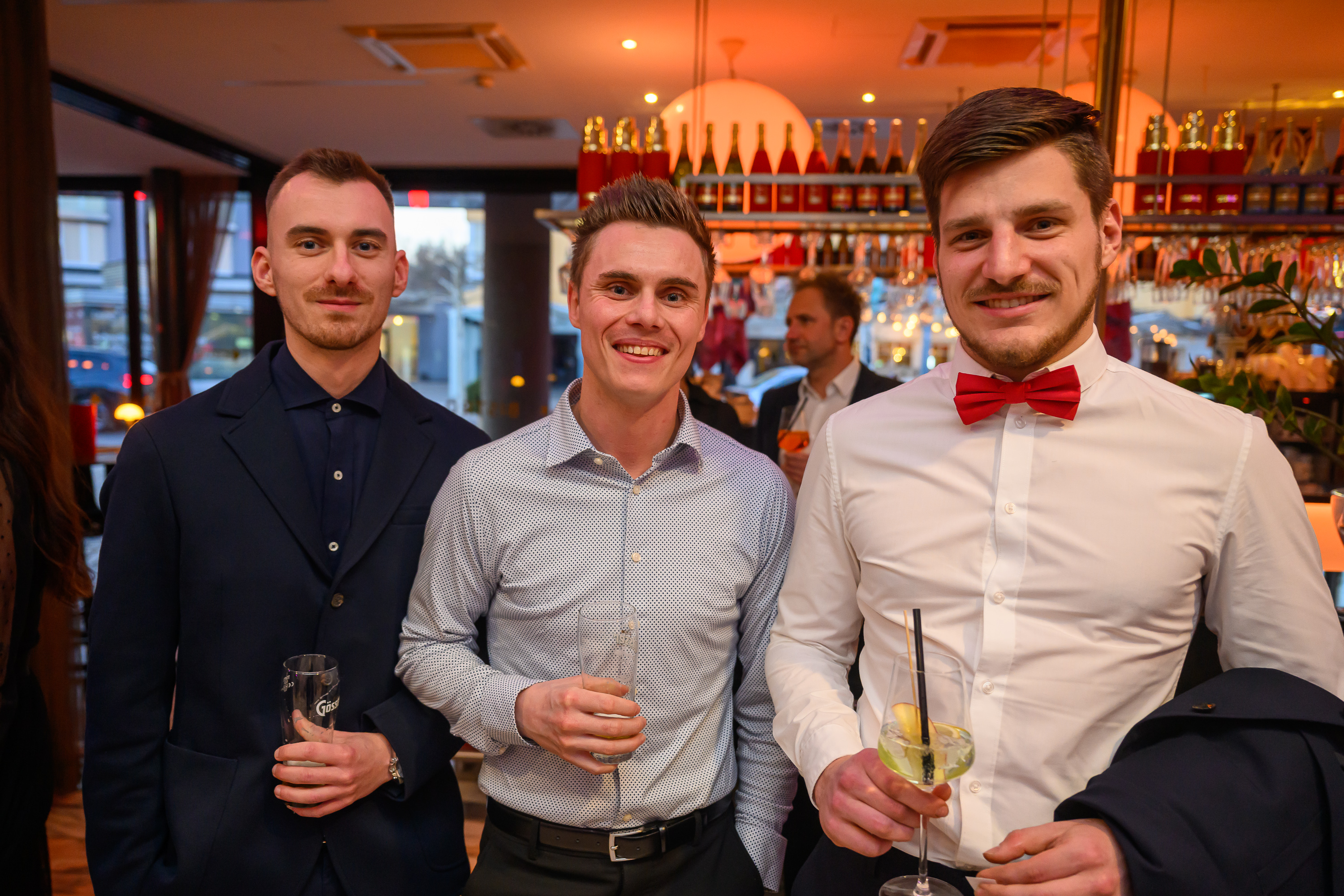 3 junge M&auml;nner in Hemd, einer tr&auml;gt eine rote Fliege