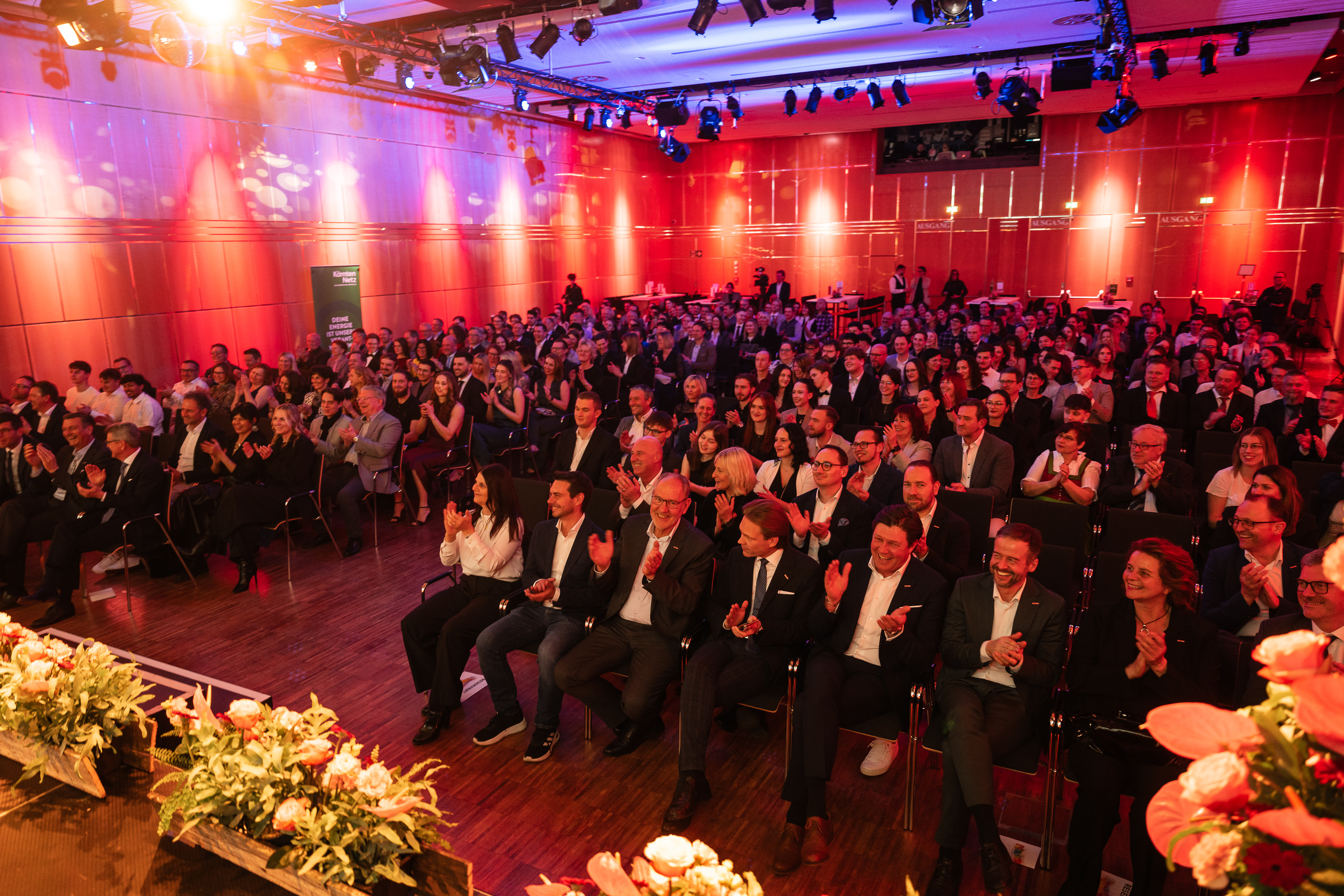 Publikum sitzend in einem rot beleuchteten Saal