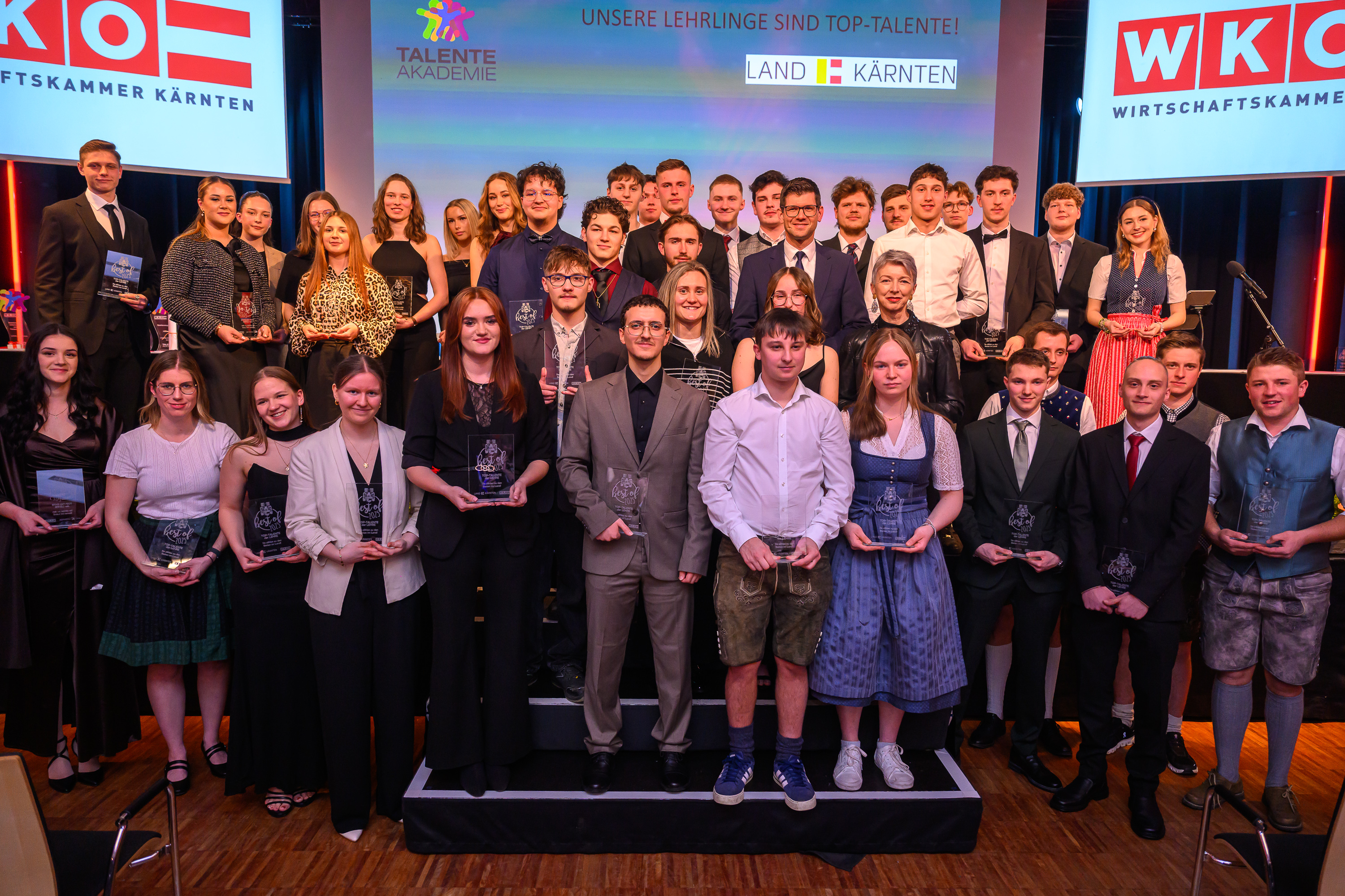 viele junge Menschen auf einer B&uuml;hne posieren f&uuml;r das Foto vor einer Leinwand