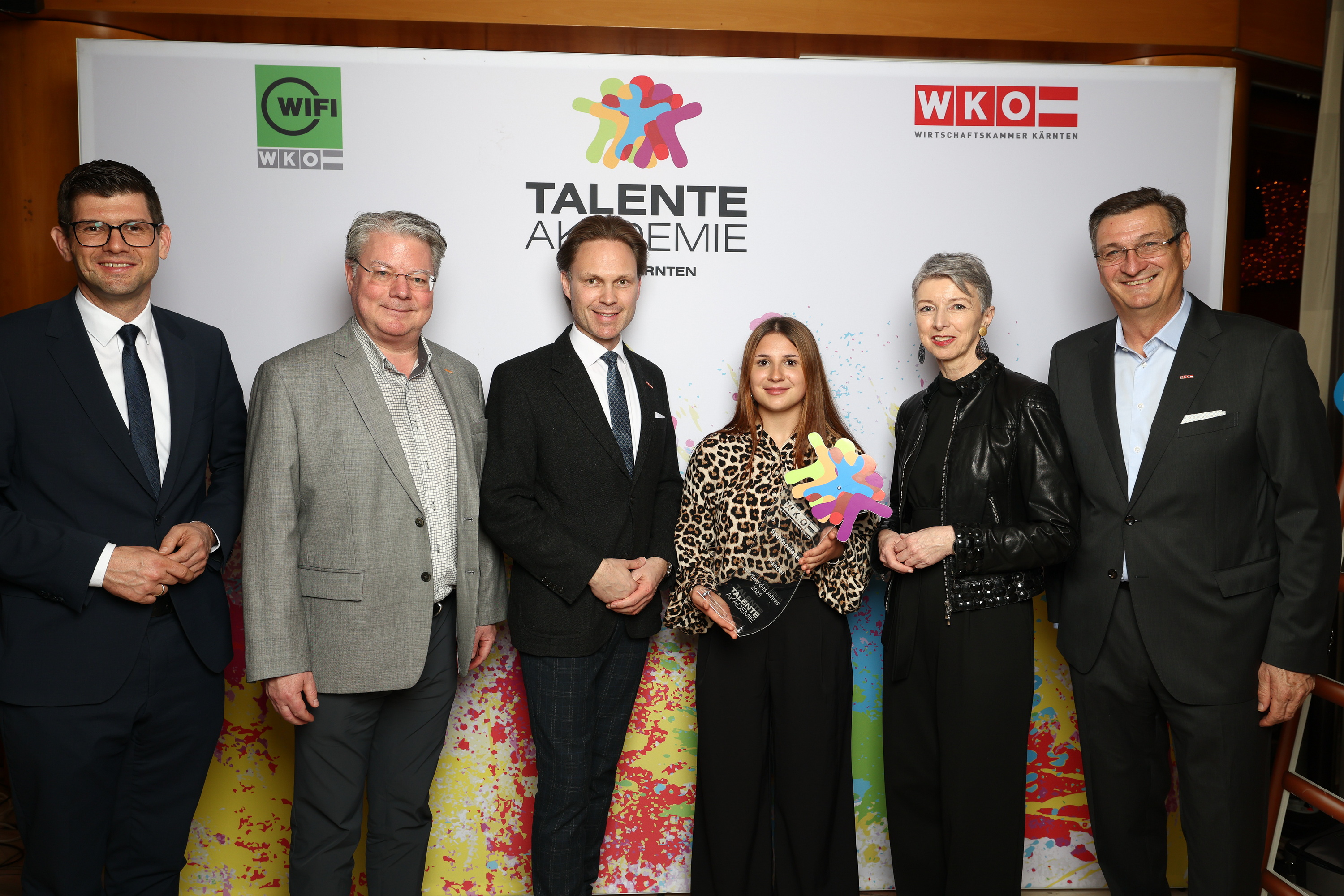 4 M&auml;nner und 2 Frauen posieren f&uuml;r ein Foto vor einer Fotowall