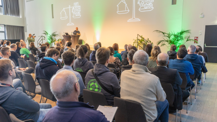 Blick vom Publikum auf eine Bühne mit einem Speaker