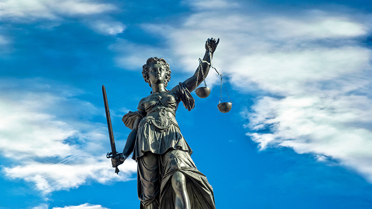 Statue der G&ouml;ttin Justitia, im Hintergrund blauer Himmel