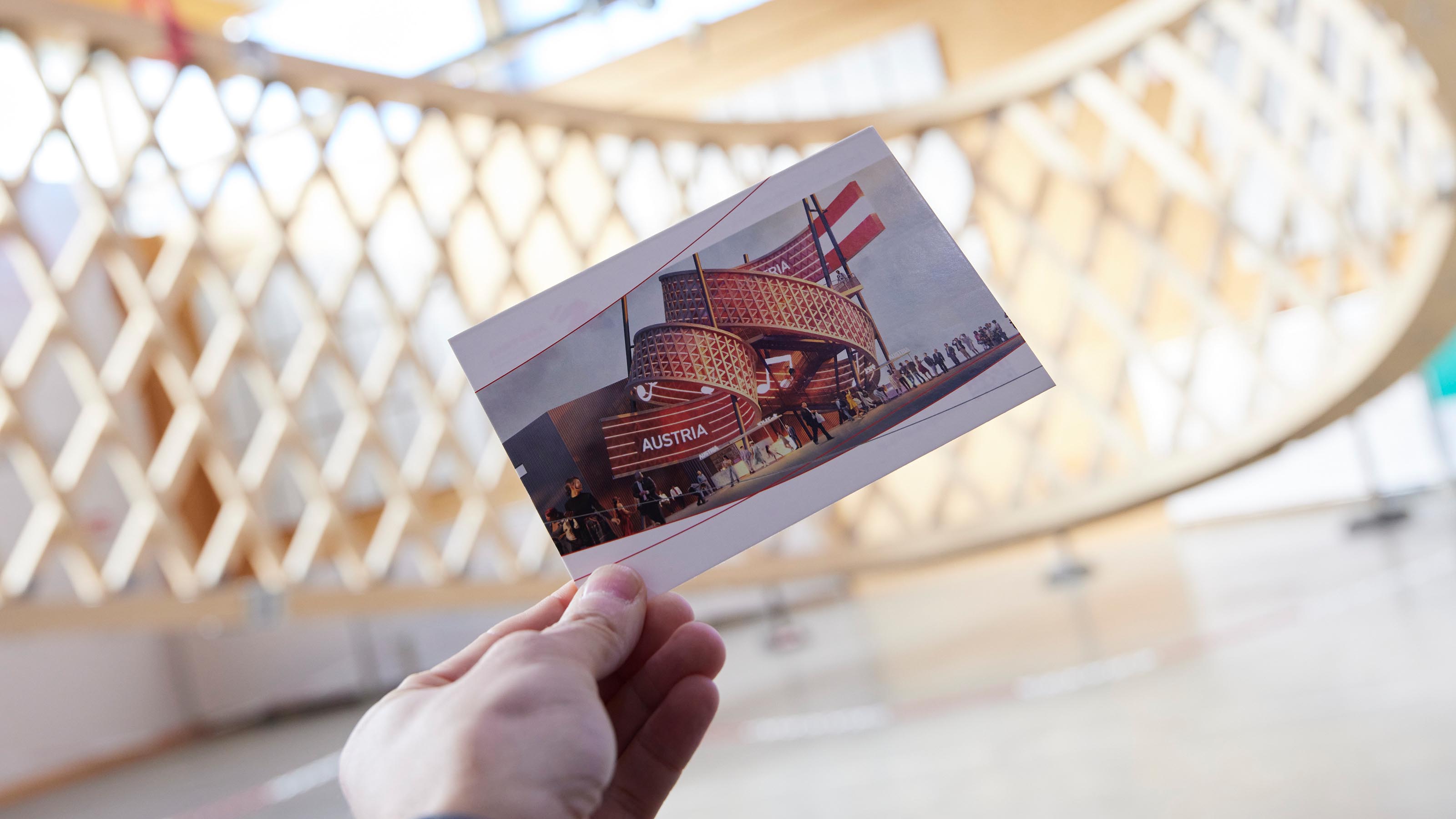 Eine Hand h&auml;lt ein Foto vom Pavillion - dahinter die rohen Holzteile