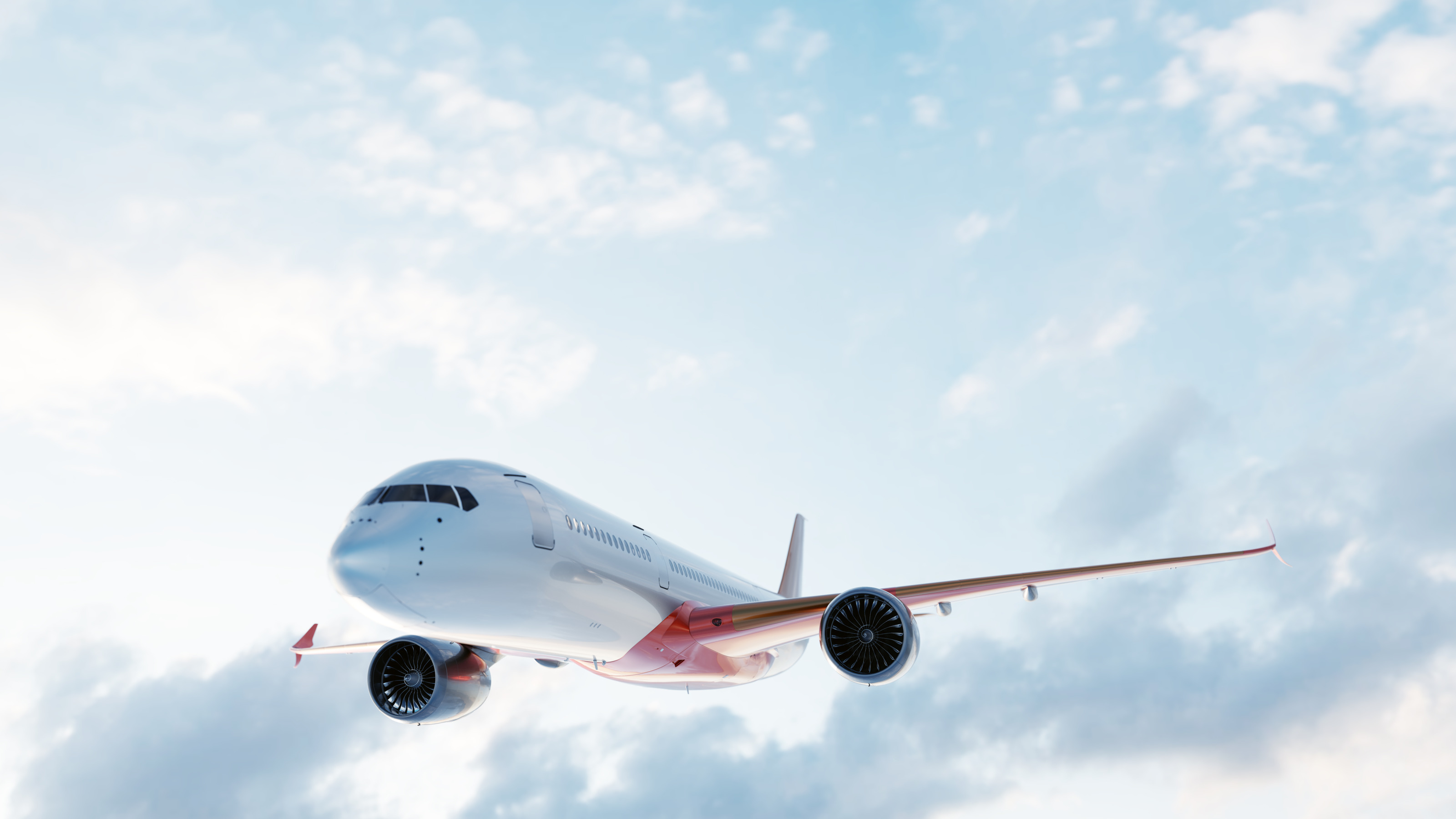 Ein rot-wei&szlig;es Flugzeug schwebt in der Luft. Im Hintergrund ist der bew&ouml;lkte Himmel.