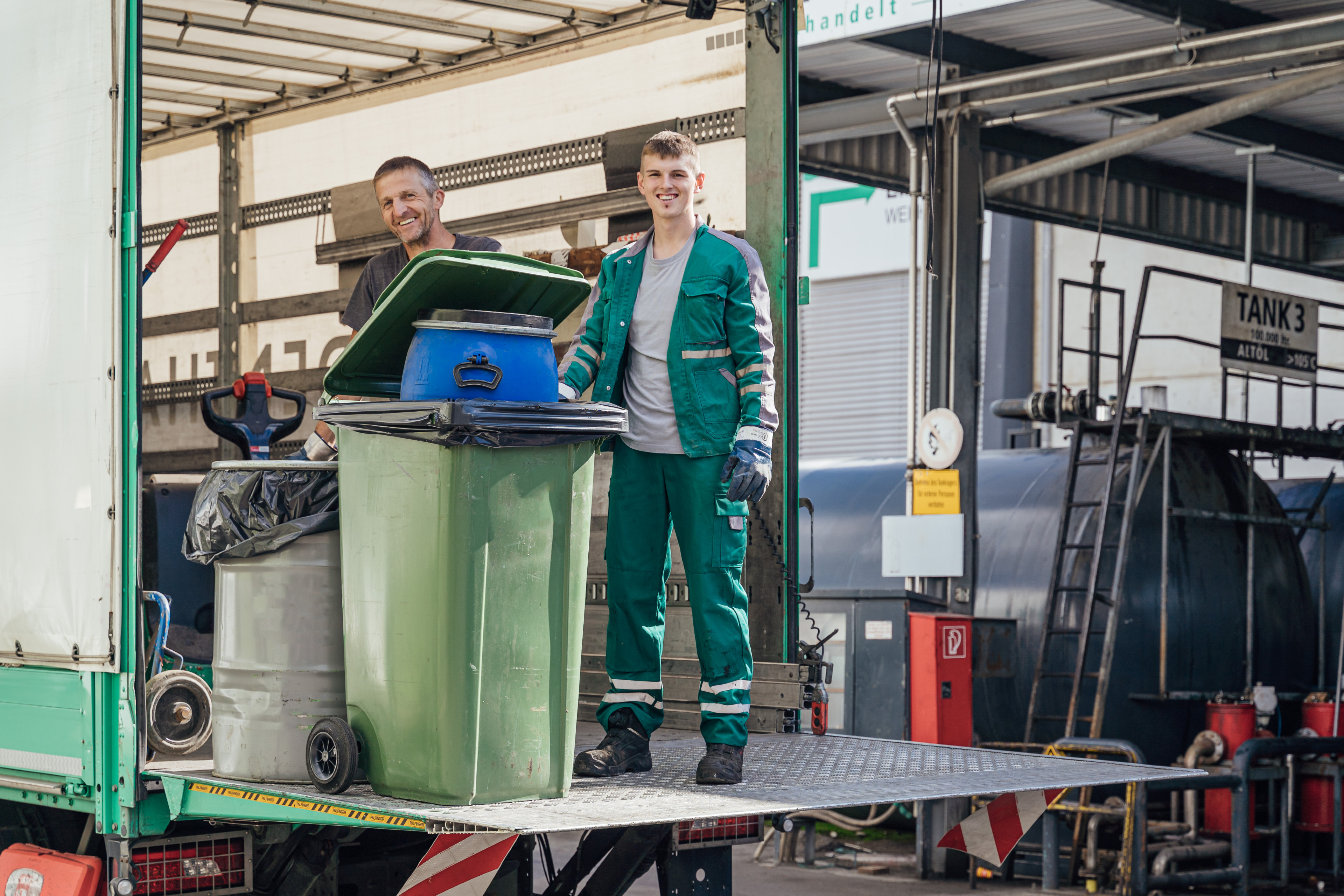 Zwei Personen neben einer M&uuml;lltonne