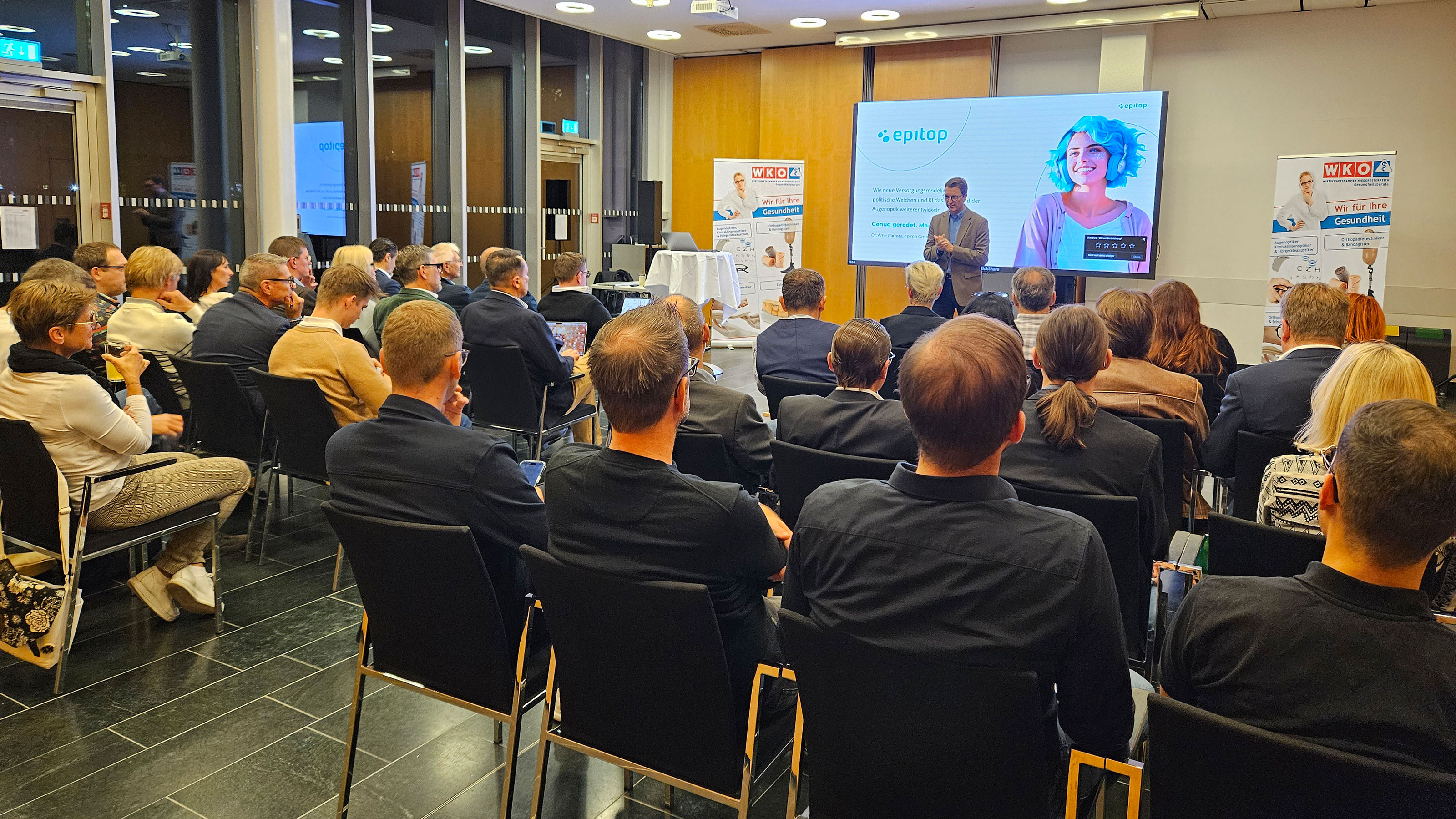 Veranstaltungssaal mit Vortragenden im Vordergrund