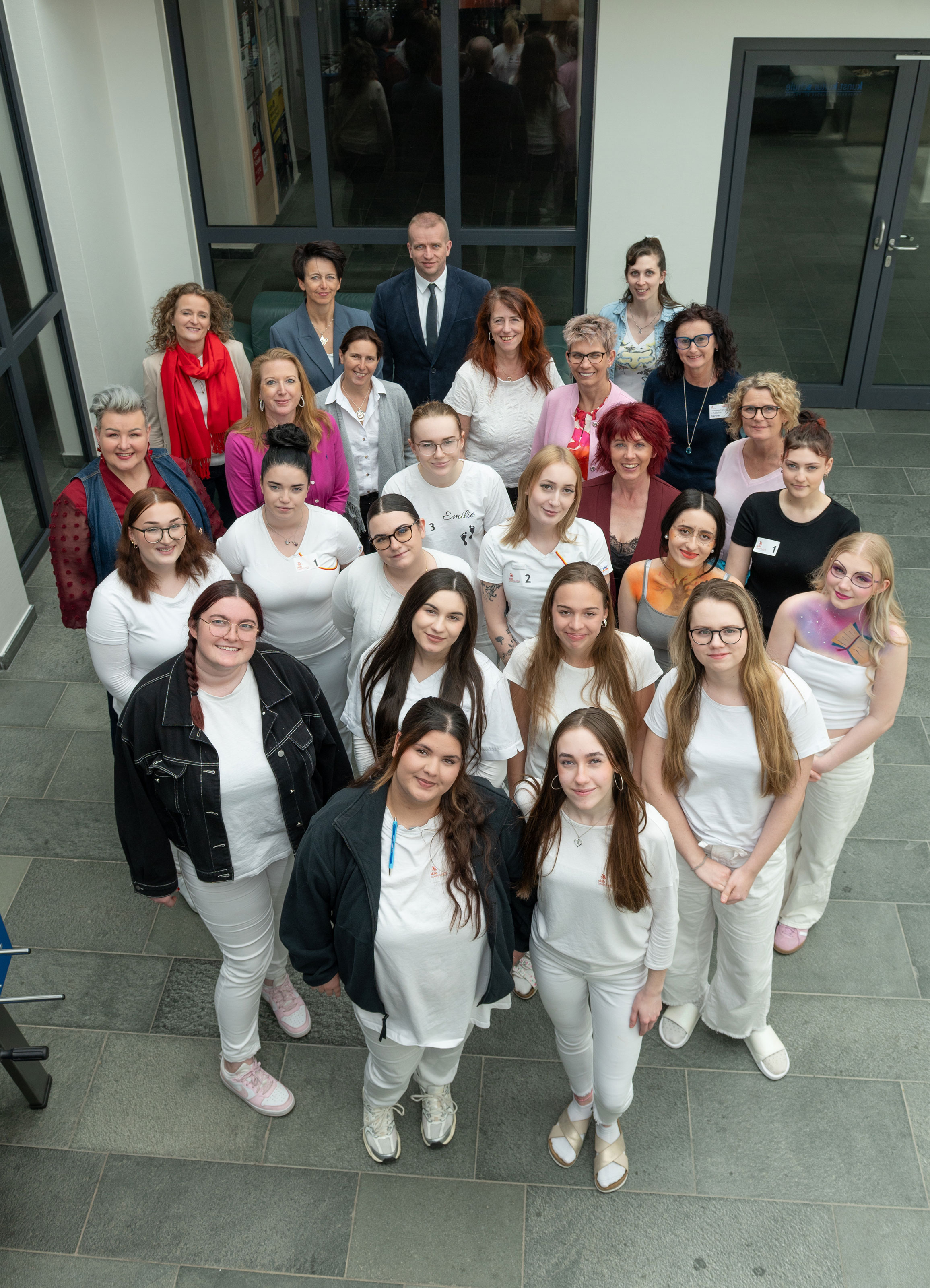 Gruppe von rund 25 Personen steht f&uuml;r ein Gruppenfoto vor dem Eingang eines modernen Geb&auml;udes