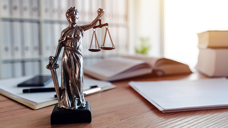 Statue der Göttin Justitia auf Schreibtisch stehend