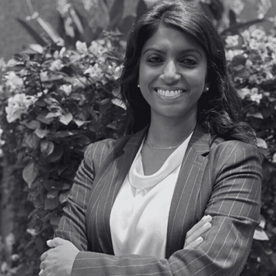 Portr&auml;t einer l&auml;chelnden Person mit verschr&auml;nkten Armen, hellem Oberteil, gestreiftem Sakko, Kette und offenen Haaren